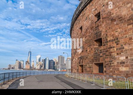 Vecchio contro nuovo, storico fortezza in mattoni Castello Williams su Governors Island sorvegliando il fiume Hudson con vista dei grattacieli di Manhattan nella ba Foto Stock