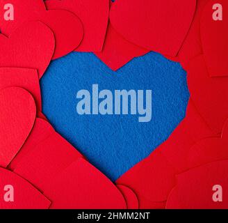 Carta tagliato rosso cuori cornice su sfondo blu testurizzato con spazio copia. Immagine concettuale. San Valentino, giorno della madre, biglietti di auguri di compleanno, Incitat Foto Stock