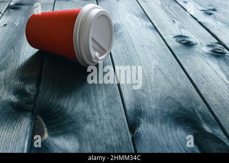 Tazza usa e getta di carta su un tavolo di legno scuro in un caffè. Messa a fuoco selettiva, spazio di copia. Foto Stock