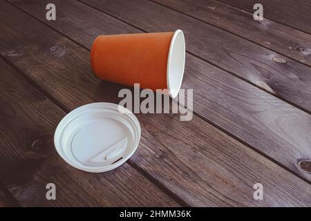 Tazza usa e getta di carta da caffè su un tavolo di legno scuro. Tonalità seppia, spazio di copia. Foto Stock