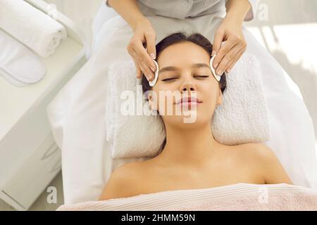 Donna felice che ottiene il suo trucco rimosso prima del trattamento facciale al centro di bellezza Foto Stock