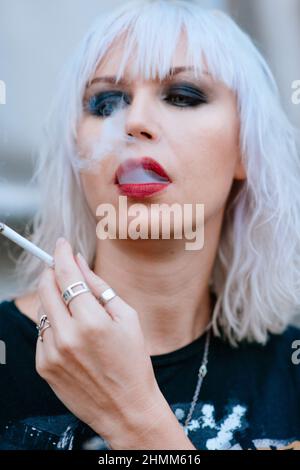 Ritratto di elegante bionda grunge giovane donna con make up fumo sigaretta Foto Stock