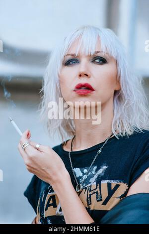Ritratto di elegante bionda grunge giovane donna con make up fumo sigaretta Foto Stock