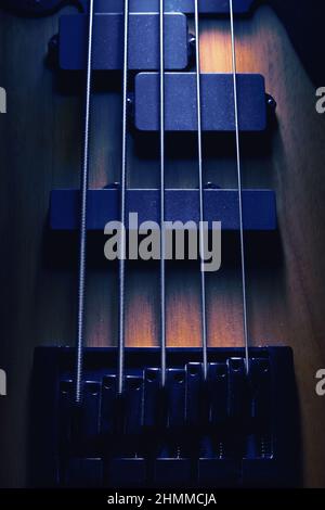Primo piano del ponte e pickup di cinque corde di chitarra basso, forme evidenziate. Foto Stock
