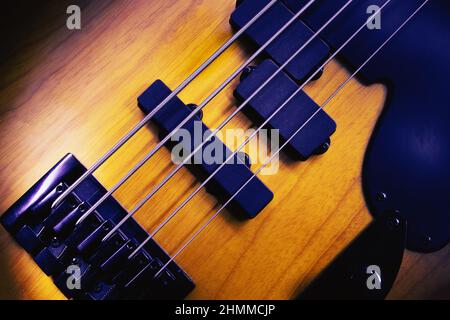 Primo piano del ponte e pickup di cinque corde di chitarra basso, forme evidenziate. Foto Stock