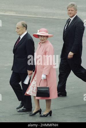 Omaha Beach, 50th anni degli sbarchi del D-Day (Normandia, Francia nord-occidentale), 1994/06/06: Regina Elisabetta II indossando un abito rosa con un cappello di corrispondenza in occasione della cerimonia internazionale. Qui, accolto dal presidente francese Francois Mitterrand e da Bill Clinton, presidente degli Stati Uniti Foto Stock