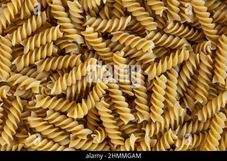 Rotini. Fusilli crudi con fondo di avena. Trama astratta della pasta. Modello di macaroni a spirale. Sfondo di cibo caldo. Tagliatelle non cotte. Mangiare sano Foto Stock