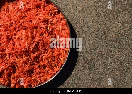 Preparazione di verdure di carota grattugiate fresche per preparare ricette di carota come gajar ka halwa. Carota grattugiata in piatto Foto Stock