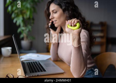 Dipendente femminile con sindrome del tunnel carpale che esercita con anello di forza di presa sul posto di lavoro Foto Stock