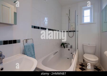 Hemingford Grey, Cambridgeshire - Feb 10 2018: Piccolo bagno piastrellato bianco e wc con piastrelle in vetro blu Foto Stock