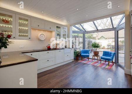 Hemingford Grey, Cambridgeshire - Feb 10 2018: Cucina moderna e alla moda in stile tradizionale con due poltrone blu e grandi finestre Foto Stock