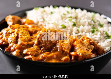 Pollo al burro indiano in una ciotola nera su sfondo nero Foto Stock