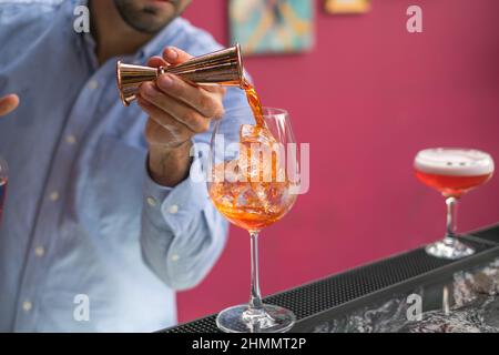 Il barista fa Aperol spritz cocktail estivo in un bicchiere di mister. Primo piano foto, processo, barra. Foto di alta qualità Foto Stock