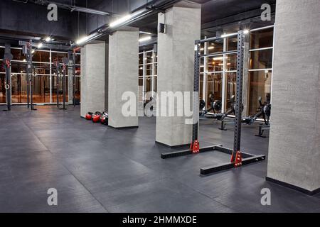 Varie macchine ginniche per l'allenamento fisico e sezione per il crossfit in un interno spazioso e vuoto con grandi finestre. Sport, fitness Foto Stock