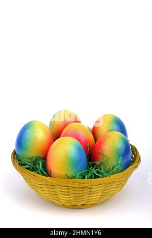 Uova di Pasqua decorate con colori vivaci in un cestino Foto Stock