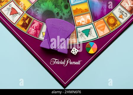 Gioco da tavolo di Trivial Pursuit gioco con dado bianco, pezzi di plastica colorata e porta carte viola su sfondo blu Foto Stock