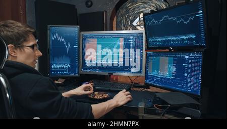 Maschio commerciante, freelancer sulle opzioni di borsa e mangia i dadi Foto Stock