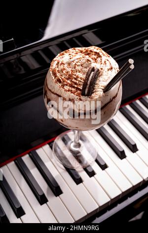 Cocktail dolce e alcolico al cioccolato guarnito con biscotto su una tastiera a piano in un night club Foto Stock