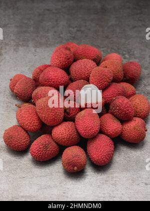 La foto mostra frutti rossi tropicali - lychee. Piatti esotici sullo sfondo color caffè. La foto è fatta in alta qualità. Foto Stock