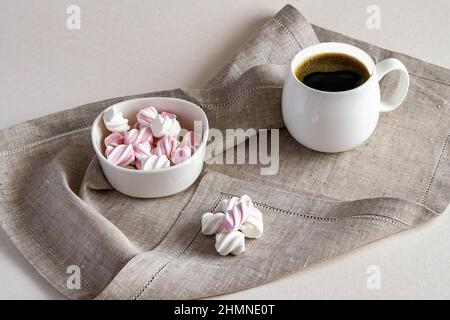 Caffè fragrante caldo e marshmallow dolce in una ciotola bianca su un tovagliolo da portata di lino. Foto orizzontale. Foto Stock