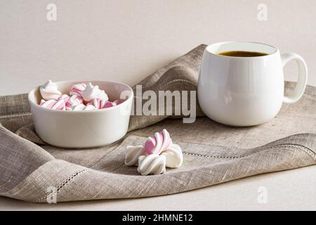 Caffè fragrante caldo e marshmallow dolce in una ciotola bianca su un tovagliolo da portata di lino. Foto orizzontale. Foto Stock