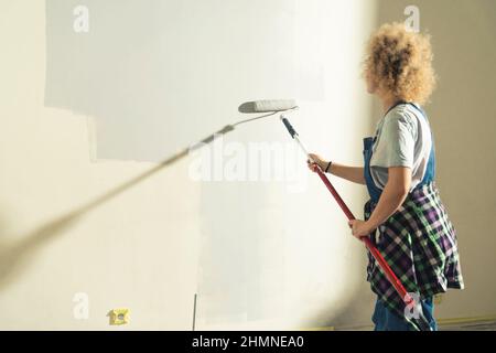 nuova ristrutturazione della casa - donna artigiana rullo pittura il muro. Foto di alta qualità Foto Stock