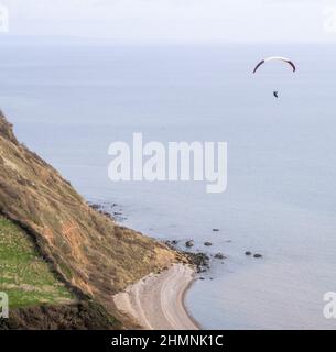 Sidmouth, Devon, 11th feb 22 Un parapendio sfrutta il caldo e fermo tempo per volare sulla bocca di Salcombe, vicino a Sidmouth. Credit: Photo Central/Alamy Live News Foto Stock