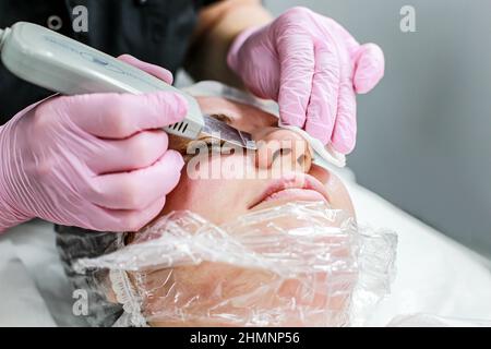 Cosmetologist ragazza fa la pulizia ultrasonica del viso Foto Stock