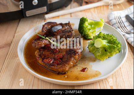 Braciole di maiale con un delizioso zucchero di canna e salsa all'aglio. Servito con broccoli su un piatto Foto Stock