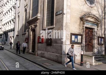 I londinesi camminano davanti alla chiesa di St. Margaret Pattens a Rood Lane, una strada medievale nella City of London, il quartiere finanziario della capitale, il 1th febbraio 2022, a Londra, Inghilterra. Rood Lane prende il nome da un crocifisso che un tempo sorgeva nel churchyard di St. Margaret Pattens, riportato da John Stow, nel 1538, per essere stato distrutto a pezzi. Foto Stock