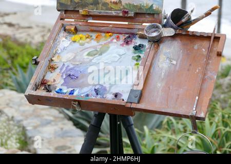 pallete di vernici ad olio, pennelli e tele su cavalletto Foto Stock