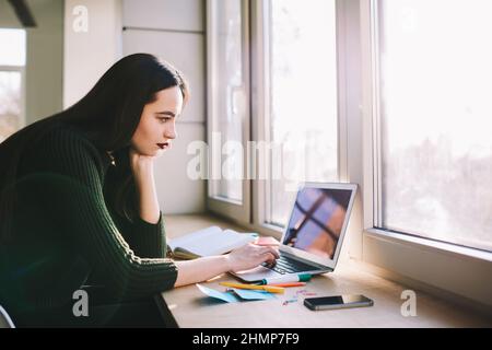 Giovane donna che studia sul laptop sul posto di lavoro Foto Stock