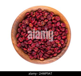 Semi di Sumac in ciotola di legno, isolati su sfondo bianco. Bacche di Rhus secche intere. Vista dall'alto. Foto Stock