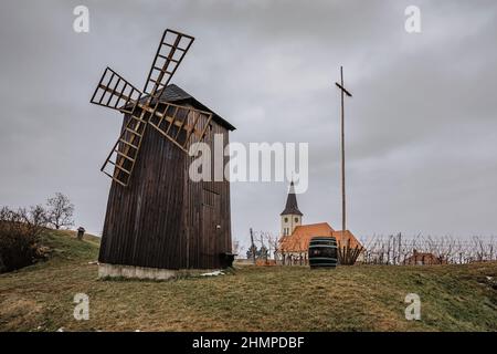 Vrbice, villaggio del vino in Moravia, Repubblica Ceca, con mulino a vento tradizionale in legno e botte di vino, chiesa in background.degustazione di vino, folklore locale.Ceco Foto Stock