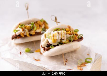 Batè bao bianco vegano fusion asiatico con carne alternativa, mayo e crunchy piccante arachidi Foto Stock