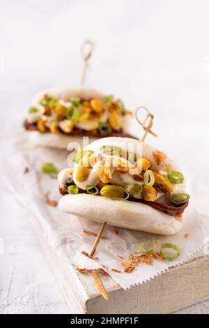 Batè bao bianco vegano fusion asiatico con carne alternativa, mayo e crunchy piccante arachidi Foto Stock