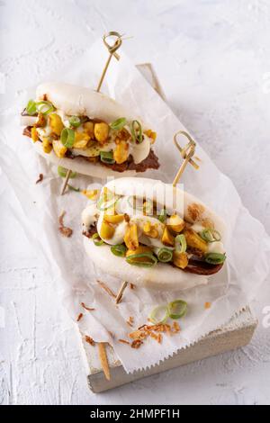 Batè bao bianco vegano fusion asiatico con carne alternativa, mayo e crunchy piccante arachidi Foto Stock