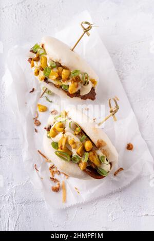 Batè bao bianco vegano fusion asiatico con carne alternativa, mayo e crunchy piccante arachidi Foto Stock