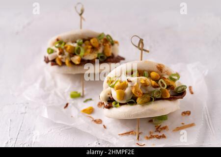 Batè bao bianco vegano fusion asiatico con carne alternativa, mayo e crunchy piccante arachidi Foto Stock