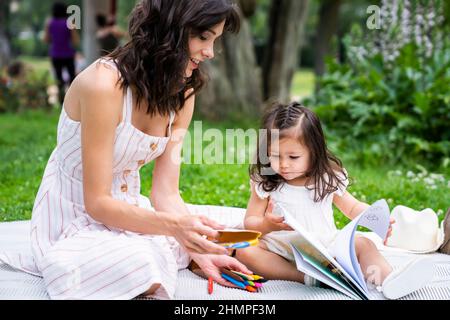 Madre e figlia rilassarsi e disegnare nel parco Foto Stock