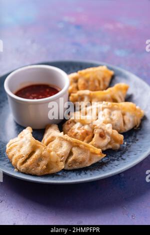 Gnocchi senza carne di vegano a fusione asiatica con salsa di sesamo caldo dolce su blu e viola Foto Stock