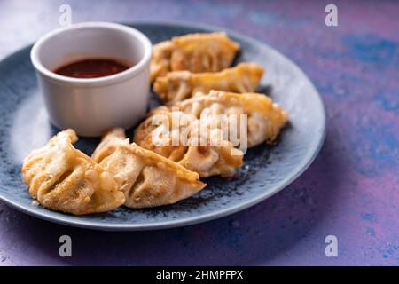 Gnocchi senza carne di vegano a fusione asiatica con salsa di sesamo caldo dolce su blu e viola Foto Stock