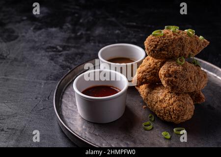 Bastoncini di jackfruit senza carne con salsa di sesamo calda dolce e salsa di barbecue vegano fusion asiatica Foto Stock