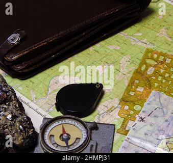 Strumenti geologici di lavoro sul campo: cartografia, bussola, lente d'ingrandimento, campioni di roccia, mappe topografiche e geologiche Foto Stock