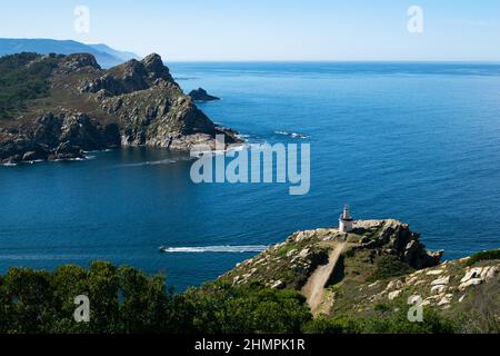 Barca che naviga oltre un faro e l'isola meridionale delle Isole Cies, Galizia, Spagna Foto Stock