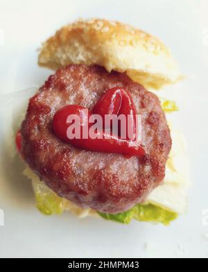 Vista dall'alto di un hamburger con ketchup di pomodoro a forma di cuore Foto Stock