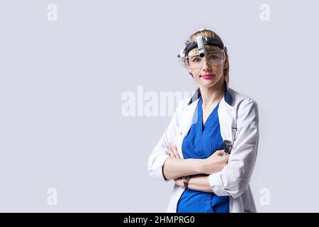Medico di fiducia che indossa la lampada frontale chirurgica e gli occhiali protettivi. Ritratto di otolaringologo femminile o chirurgo capo e collo Foto Stock