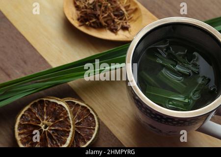Goiânia, Goias, Brasile – 11 febbraio 2022: Una tazza di tè, con foglie di citronella, alcune fette di arancia disidratata, un cucchiaio con erbe. Foto Stock