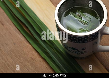 Goiânia, Goias, Brasile – 11 febbraio 2022: Una tazza di tè con foglie di citronella su una superficie di legno. Foto Stock