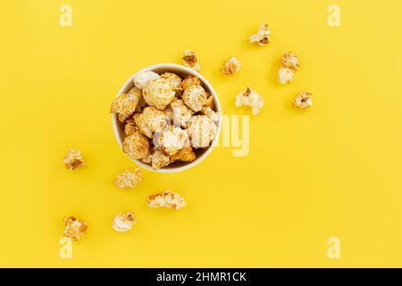 popcorn al caramello in ciotola gialla con spazio di copia per testo, primo piano, snack dolci, popcorn al caramello per guardare film, vista dall'alto Foto Stock